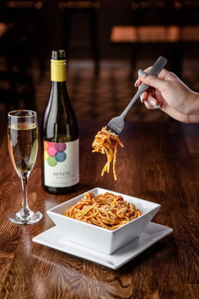 Paste italiene cu sos servite alături de un pahar de vin, într-un restaurant cu specific italian