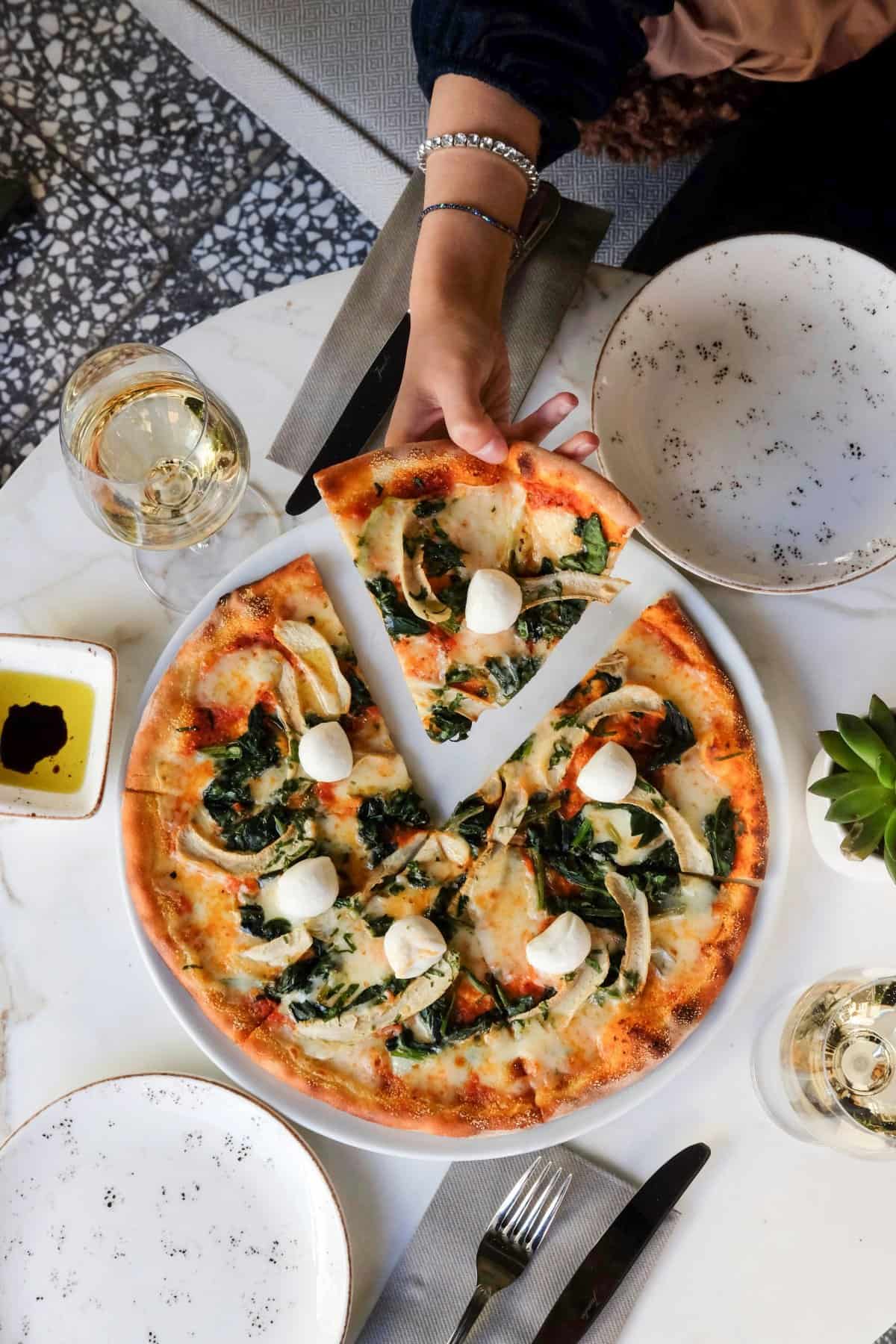 Italian pizza seen from above with a slice being served.